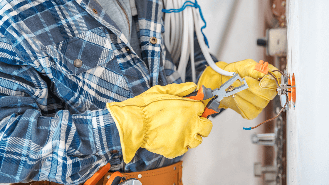 Skilled electrician cutting and splicing wires. Explore high-demand trade careers like electrician with TradeWorks USA.