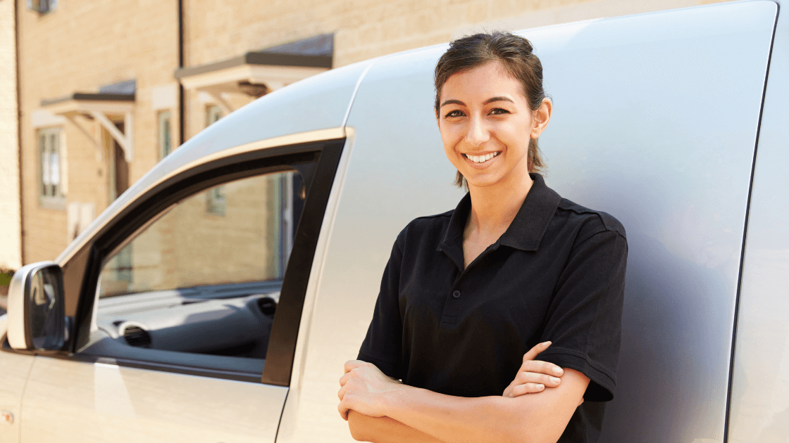 Smiling woman standing next to a van, representing career opportunities in the trades for women