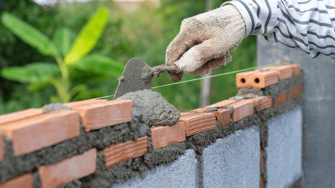 A female mason confidently laying bricks at a job site, showcasing opportunities for women in skilled trades.